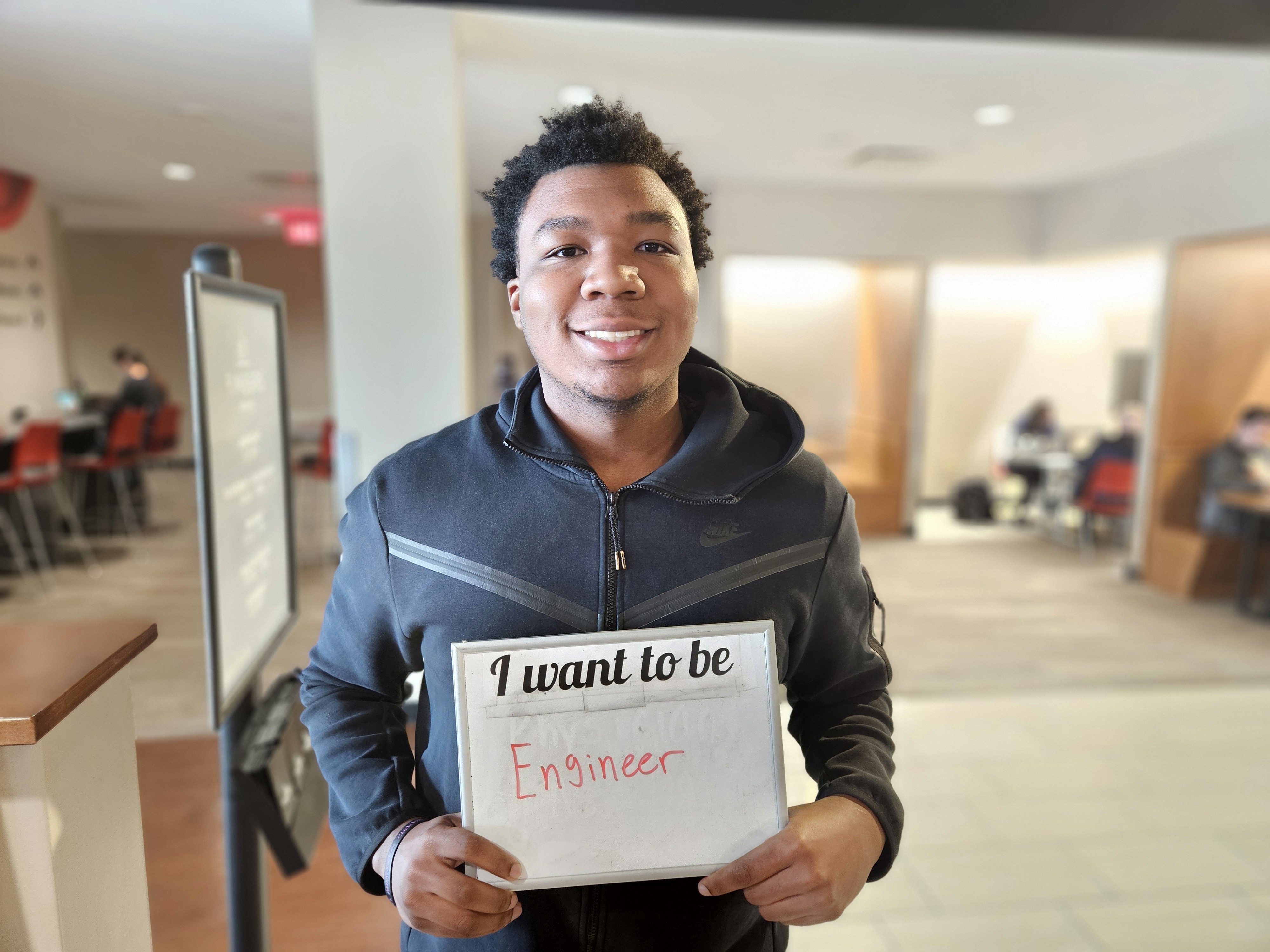 male student holding sign I want to be an engineer
